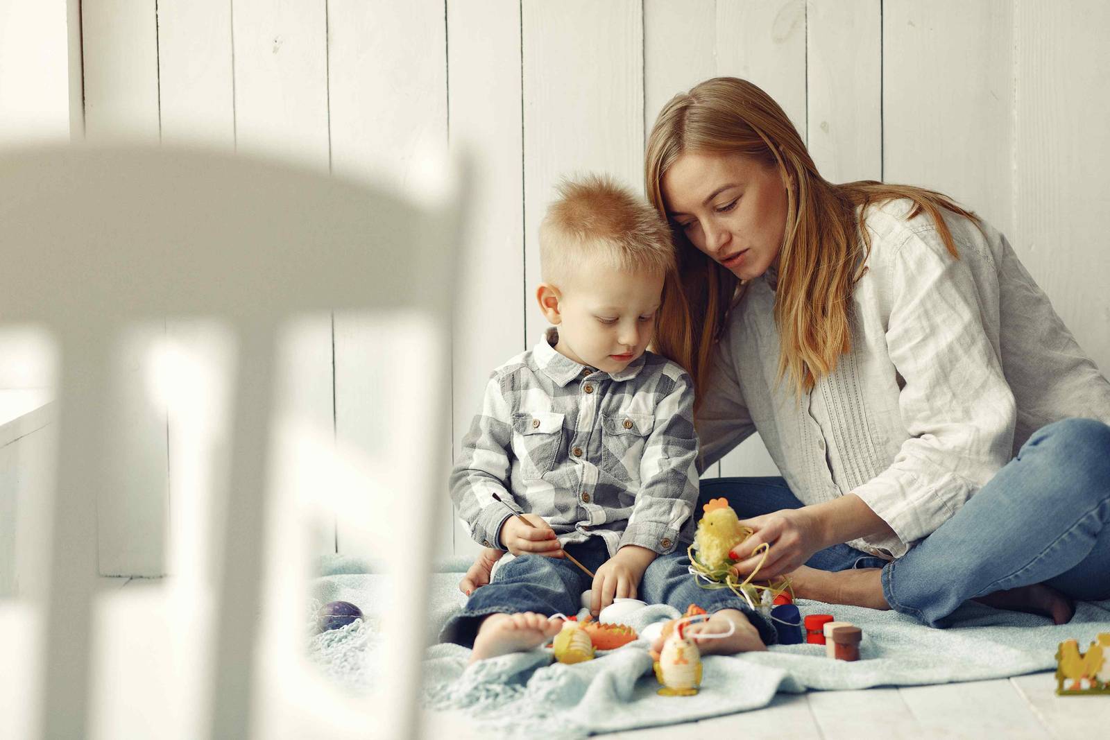 A mother and her young son playing on a blanket at home